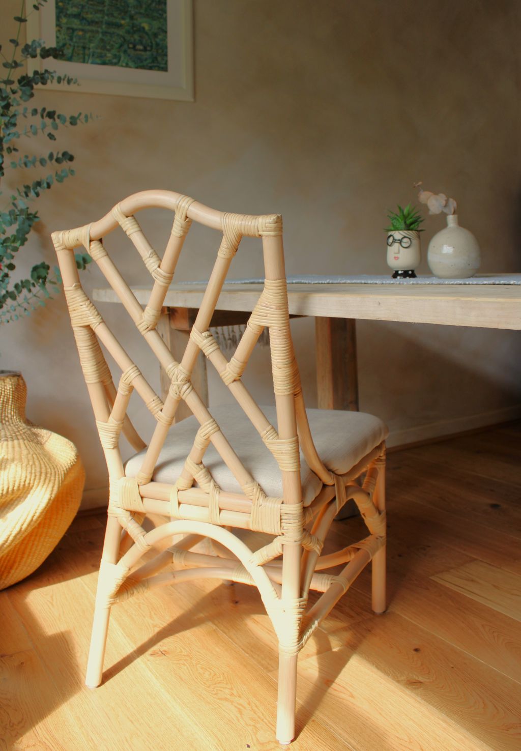 Rattan chair with a cushion in a room with a table and decorative items.