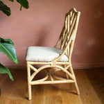 Wicker chair with a cushioned seat against a pink wall