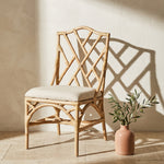 Natural Rattan chippendale style chair with a cream cushion against a pink wall