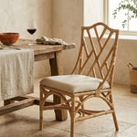 Natural Rattan chippendale style chair with a cream cushion against a pink wall