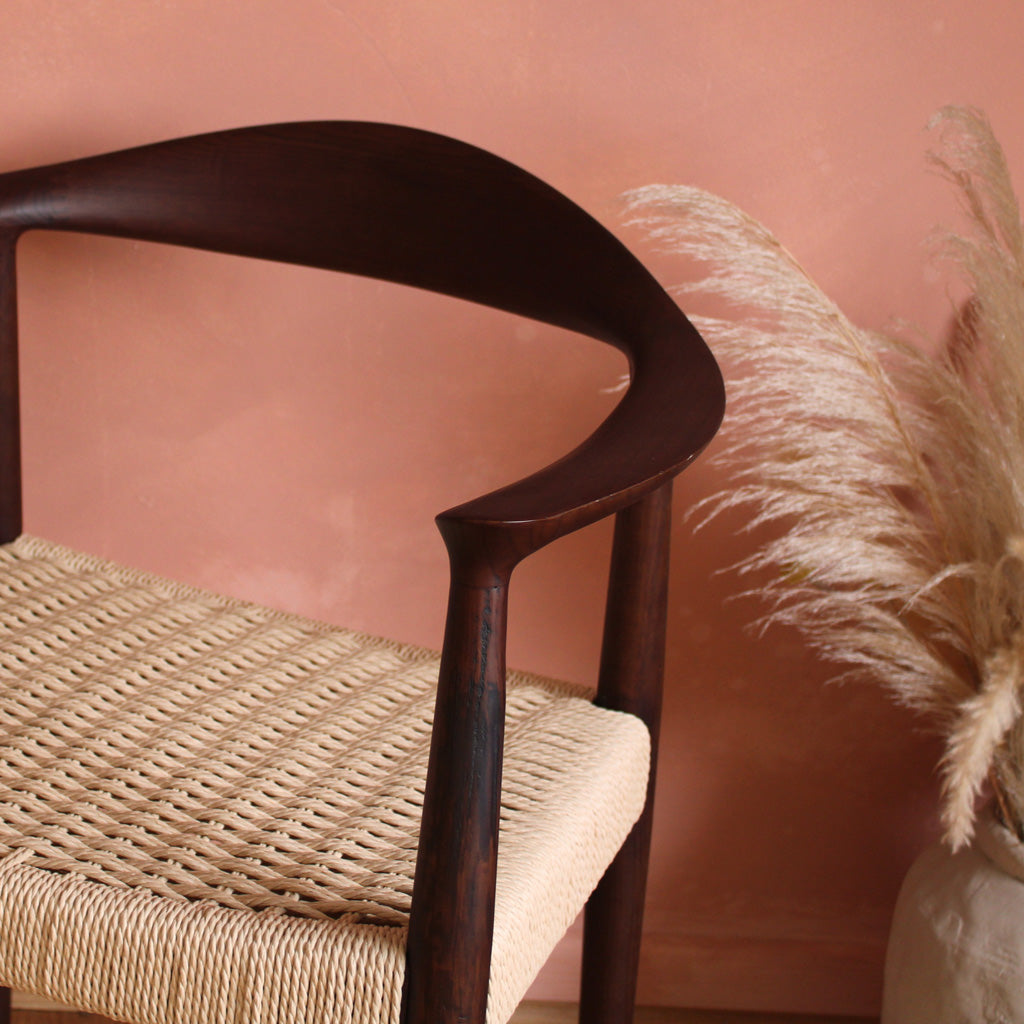 Wooden chair with woven seat in a room with wooden floor and plant- Walnut colour.