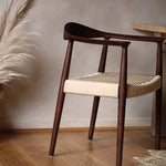 Wooden chair with woven seat in a room with wooden floor and plant- Walnut colour.