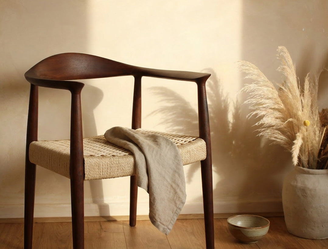 Wooden chair with woven seat in a room with wooden floor and plant- Walnut colour.