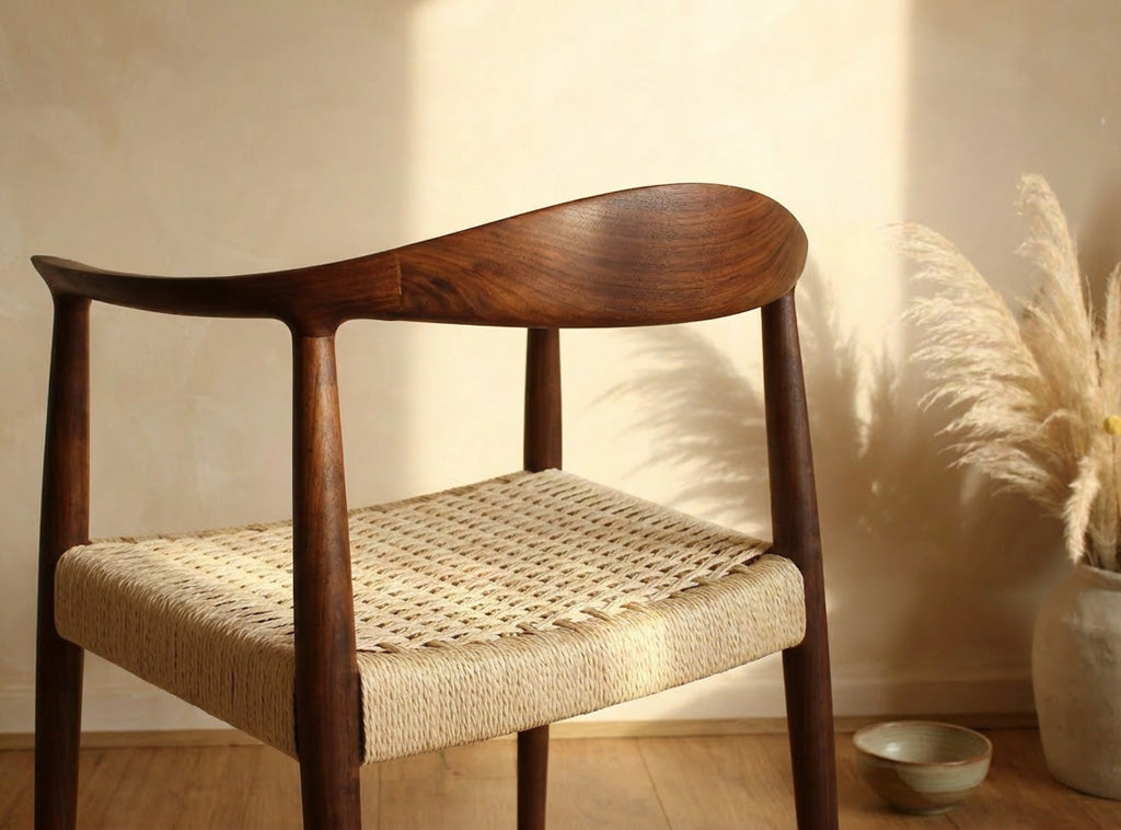 Wooden chair with woven seat in a room with wooden floor and plant- Walnut colour.