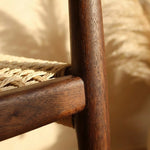 Wooden chair with woven seat in a room with wooden floor and plant- Walnut colour.