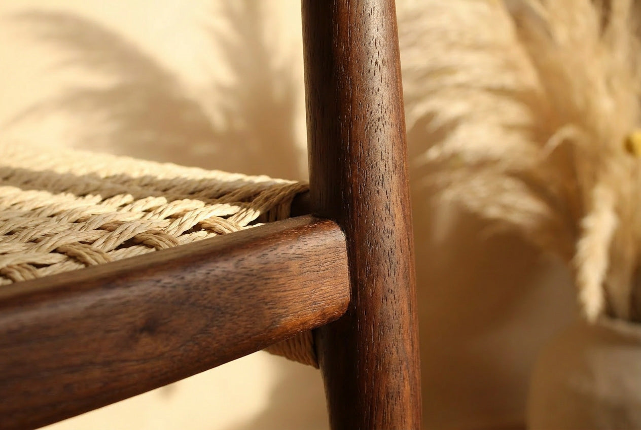 Wooden chair with woven seat in a room with wooden floor and plant- Walnut colour.